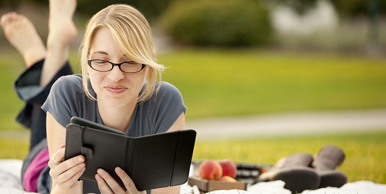 Libbyr female reading an ebook on a picnic blanket outdoors