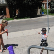Woman blows bubbles for a young child outside 
