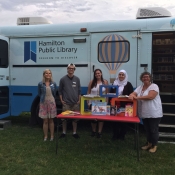 HPL staff standing infront of the Bookmobile bus with the doors open
